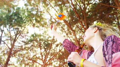 woman playing with toy windmill and having bottle of beer 4k