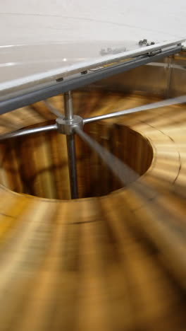 working machine for honey extracting from wooden frames with honeycombs. metal barrel with centrifuge mechanism spinning quickly the frames. top view close up. vertical video