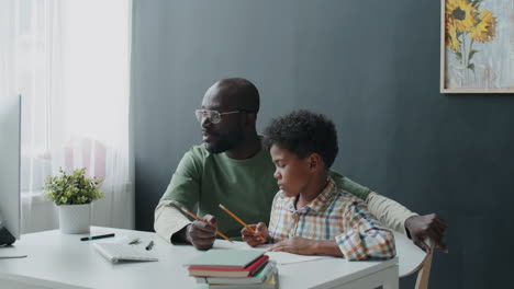 Padre-Afroamericano-Ayudando-A-Su-Hijo-A-Tomar-Lecciones-En-Línea-En-Casa