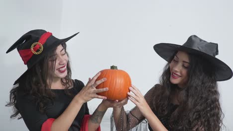 two witches holding a pumpkin