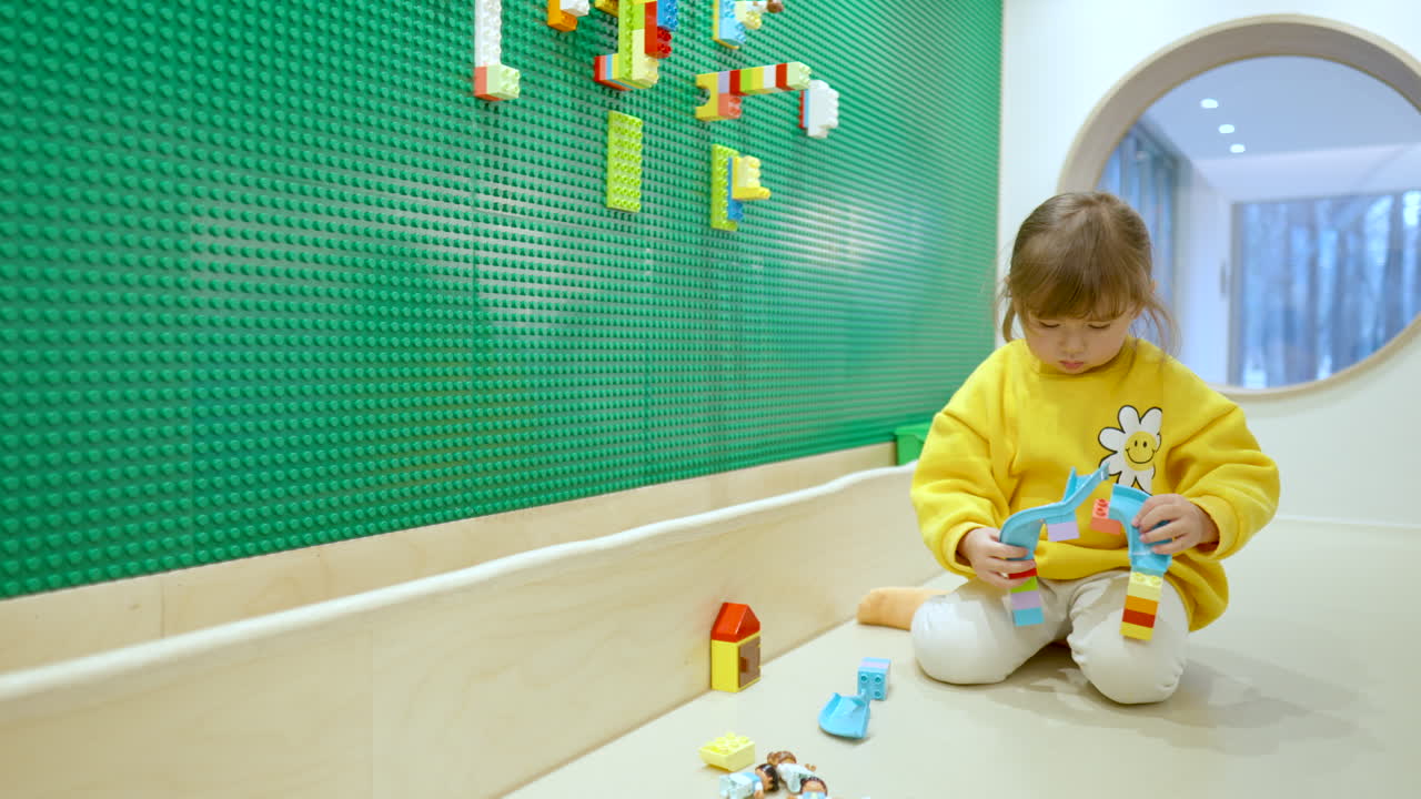 İç mekan oyun odasında renkli Lego bloklarıyla oynayan küçük kız - ağır çekim geniş açı