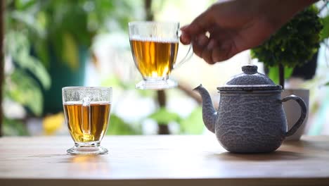 an adult hand takes a glass of tea on the table in the morning and drink it