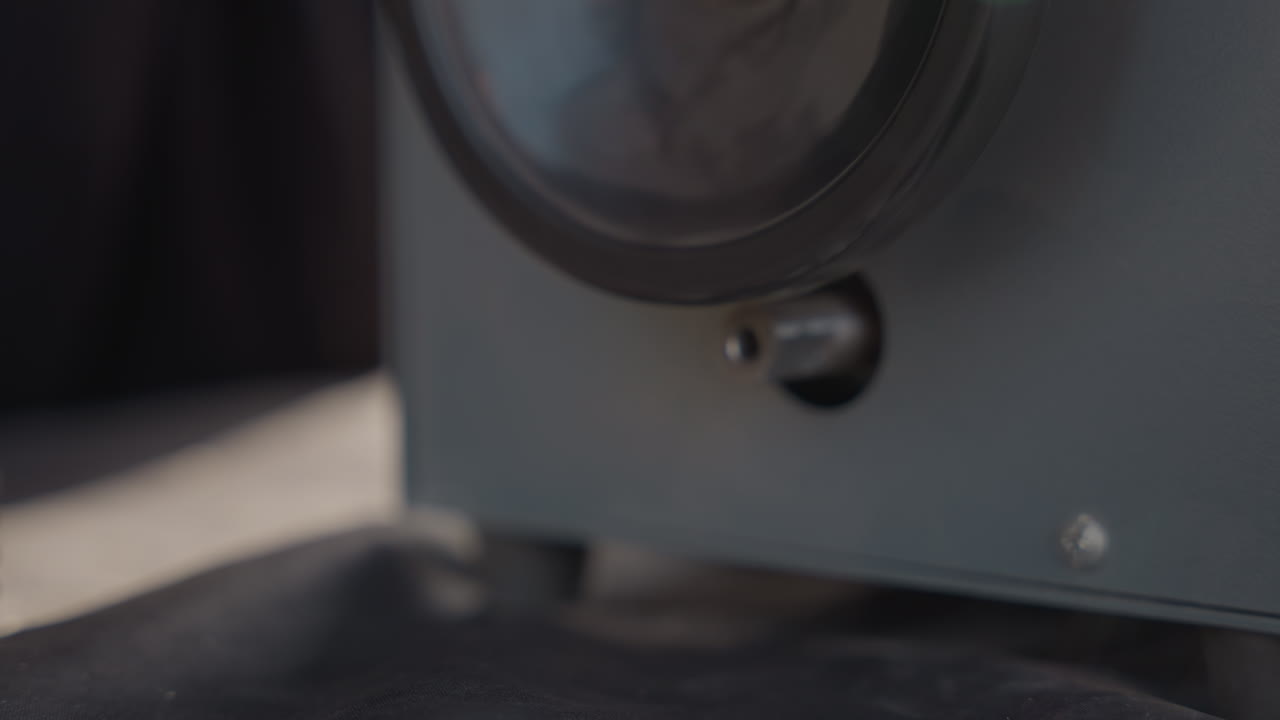 Close-up de mão ajustando o dial da máquina, calibração meticulosa em oficina silenciosa, pequeno botão de controle, rotações medidas, movimento focado e constante, alinhamento preciso para preparação de marcenaria.