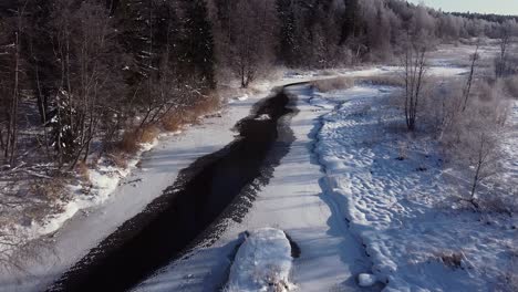 Winter-partially-frozen-river-in-forest-landscape-aerial-view