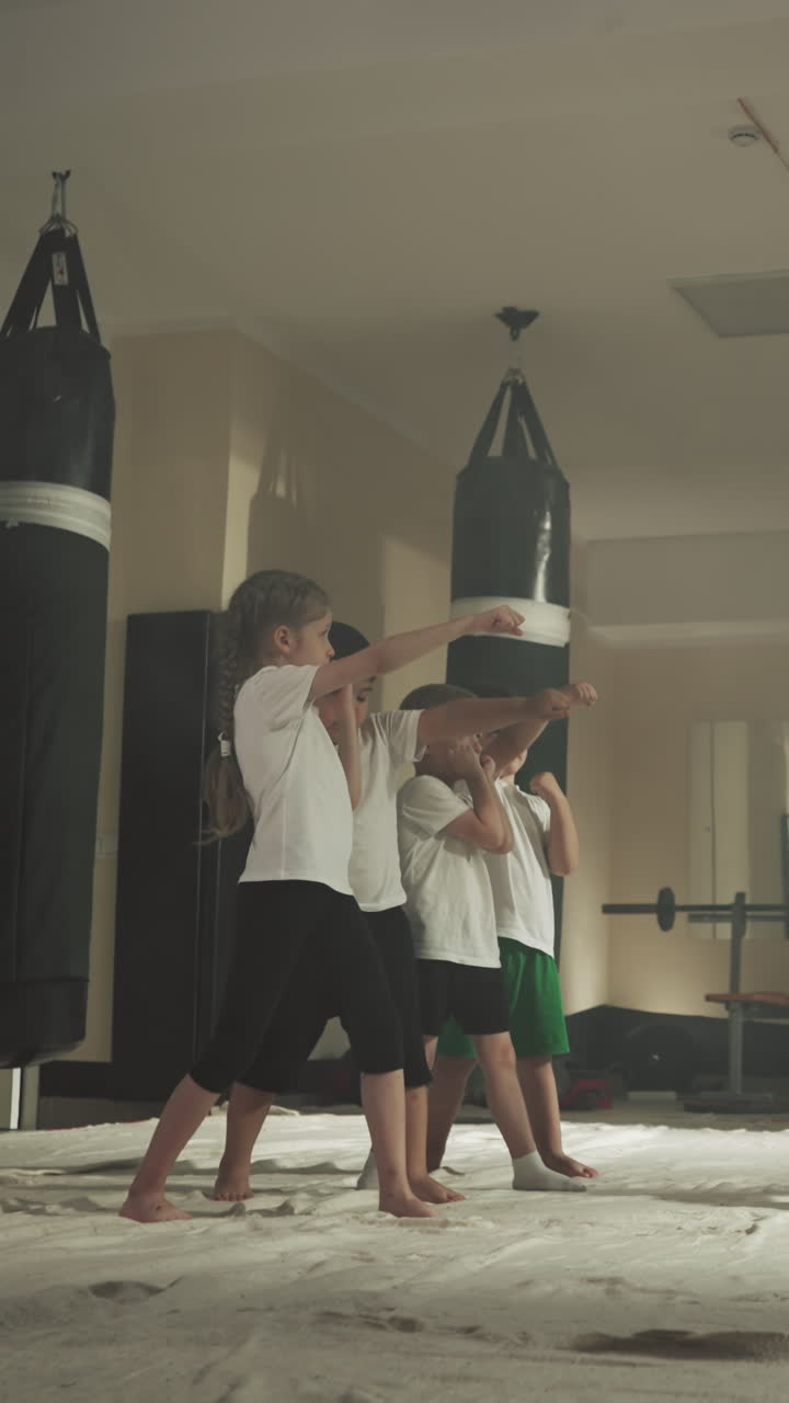 el entrenador muestra golpes a los niños en la escuela de deportes. los niños pequeños aprenden a golpear y dar pasos con un instructor hábil en el gimnasio a cámara lenta. combate de boxeo