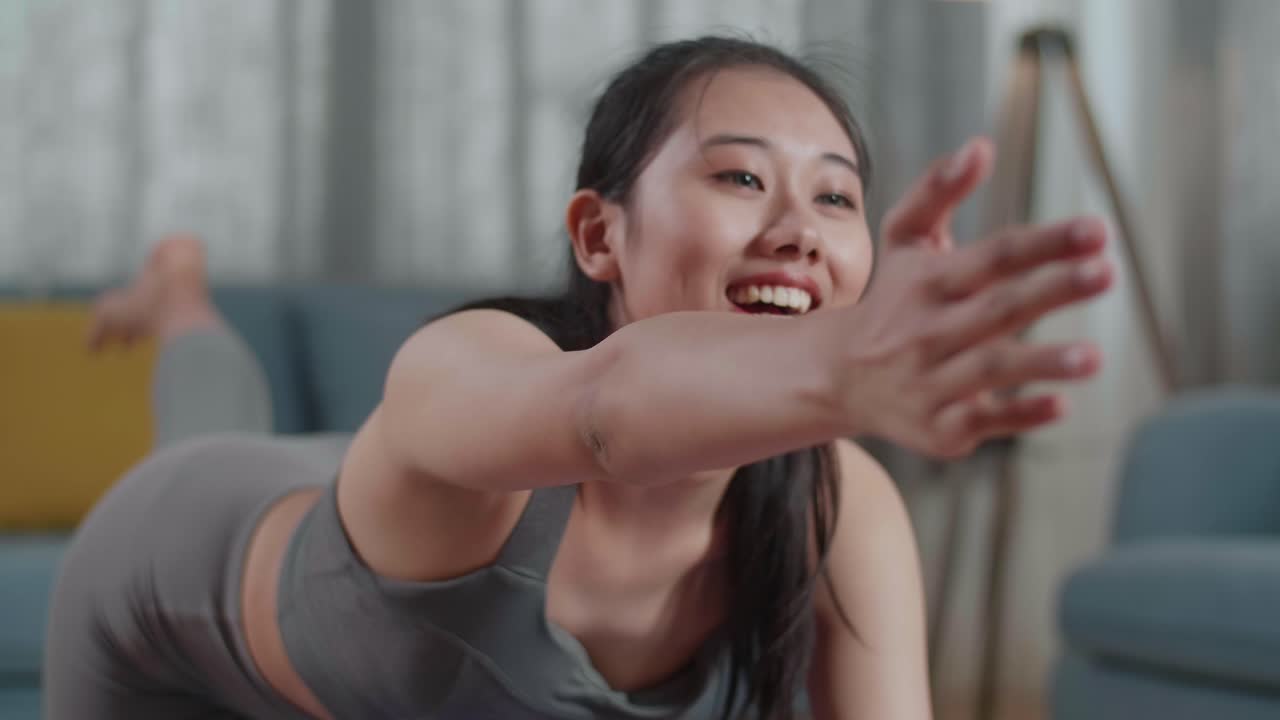 스포츠 옷을 입은 젊은 아시아 운동선수 여성이 집에서 매트 위에 균형 잡는 테이블 포즈에서 요가를 하는 근접 초상화