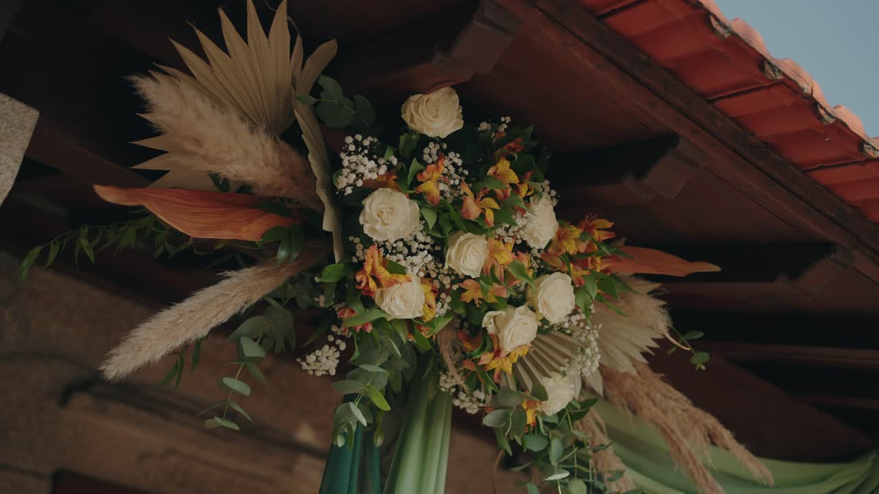 Arranjo de flores decorativo com rosas e folhagem seca presos a vigas