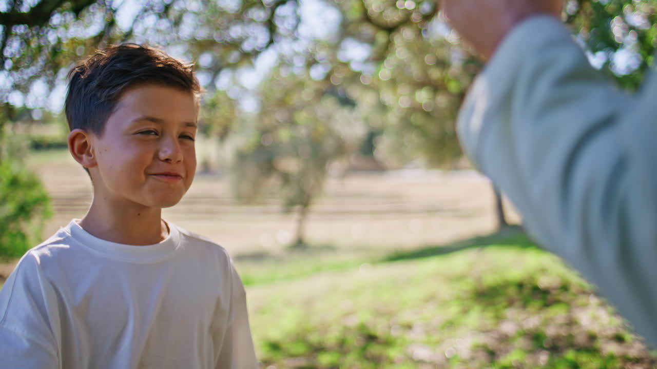 Funny kid enjoying game with unrecognizable father at sunshine nature closeup