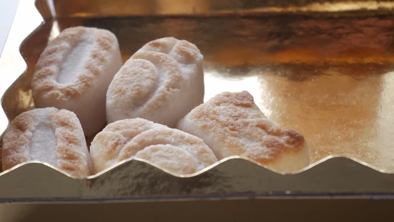 Una mano seleziona statuette di marzapane, momento delicato, focus sulla scatola dorata