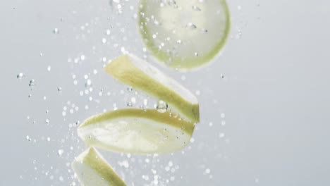 Video-of-slices-of-lime-and-lemon-falling-into-water-with-copy-space-on-white-background
