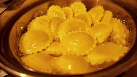 el ravioli se cocina en una sartén tambaleante de agua hirviendo a una luz cálida de cerca