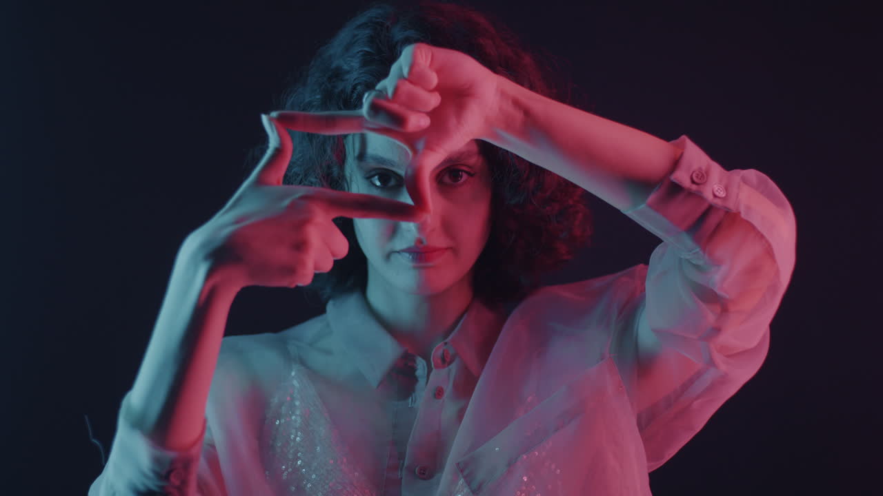 Woman Framing Her Face with Hands in Neon Light