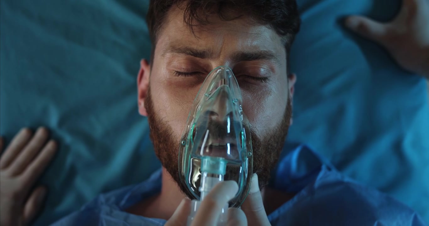 Paziente uomo con maschera per l'ossigeno sdraiato nel letto d'ospedale
