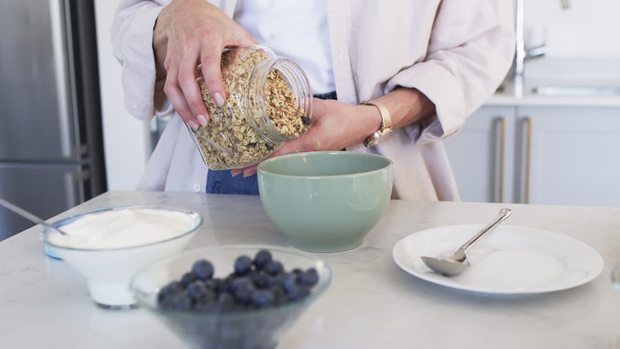 una mujer caucásica de mediana edad prepara el desayuno en una cocina moderna.
