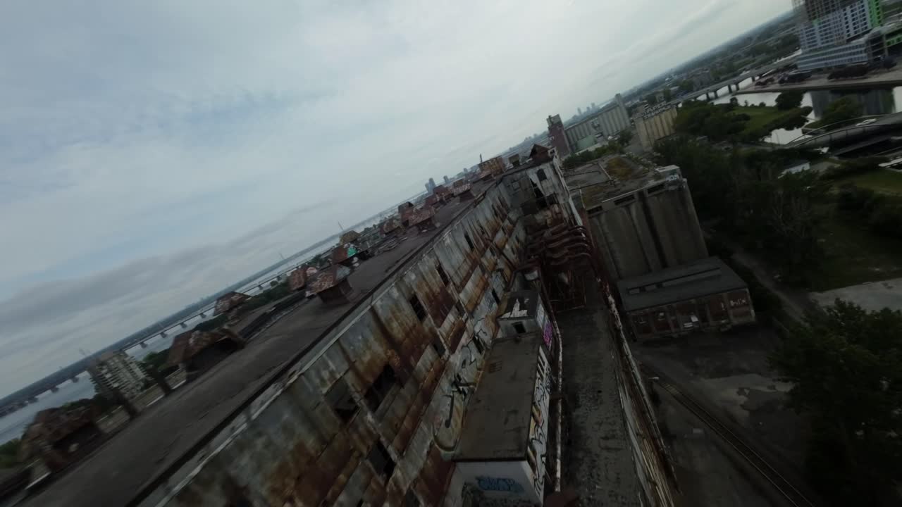 FPV drone dynamic footage circling and flying close to old industrial buildings at abandoned Silo 51 in Montreal's Old Port.