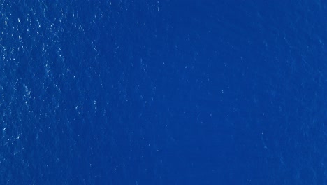 drone over deep blue ocean, vast and calm, ideal for soothing and relaxing background uses, ascend with light shimmering and sparkling
