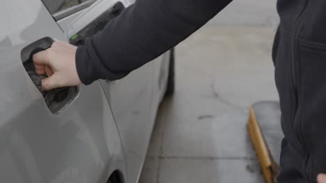 Weißer-Kaukasischer-Mann-Mit-Ehering-An-Der-Tankstelle,-Der-Ein-Silbernes-Auto-Füllt,-Den-Tankdeckel-Wieder-Aufsetzt,-Den-Tankdeckel-Schließt-Und-Dann-Staub-Und-Flusen-Vom-Auto-Wischt