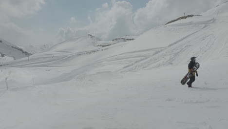 close-up of snowboarder holding snowboard and walking uphill the pistes on the snowy slopes of mount hermon, golan heights, israel