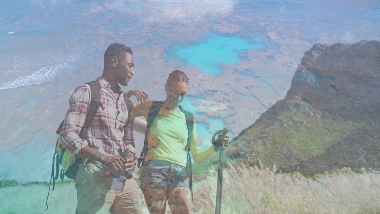 Man and woman hikers tracking health data on coastal hillside, with camera, backpack icons