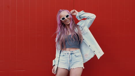 stylish young woman posing in front of a red wall