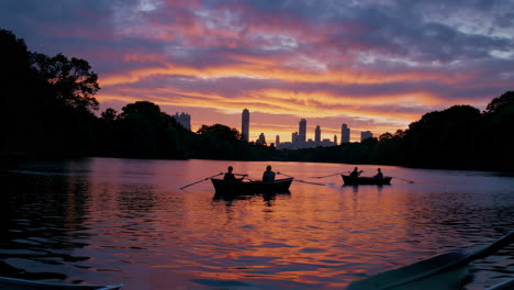 rowboats on a lake at sunset with city skyline