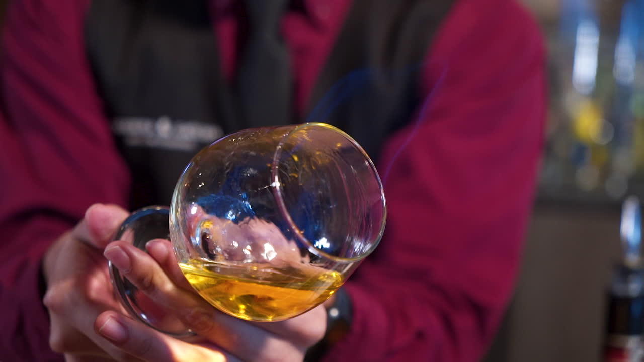 el camarero gira cuidadosamente el vaso de licor en llamas para preparar la receta de la bebida, el control deslizante se cierra a cámara lenta 4k