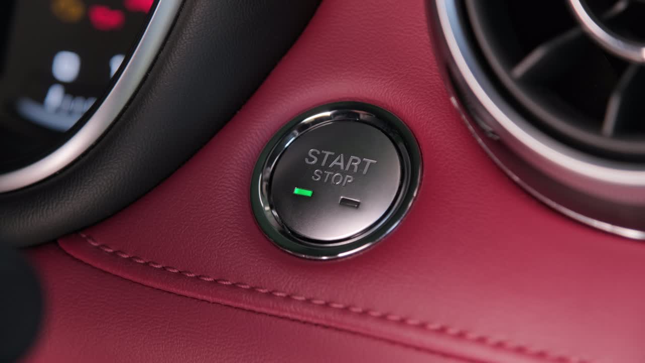 운전자의 손은 자동차 엔진을 시작하기 위해 버튼을 누르며, 엔진의 열없는 점화 시작, 교통과 기술의 개념.