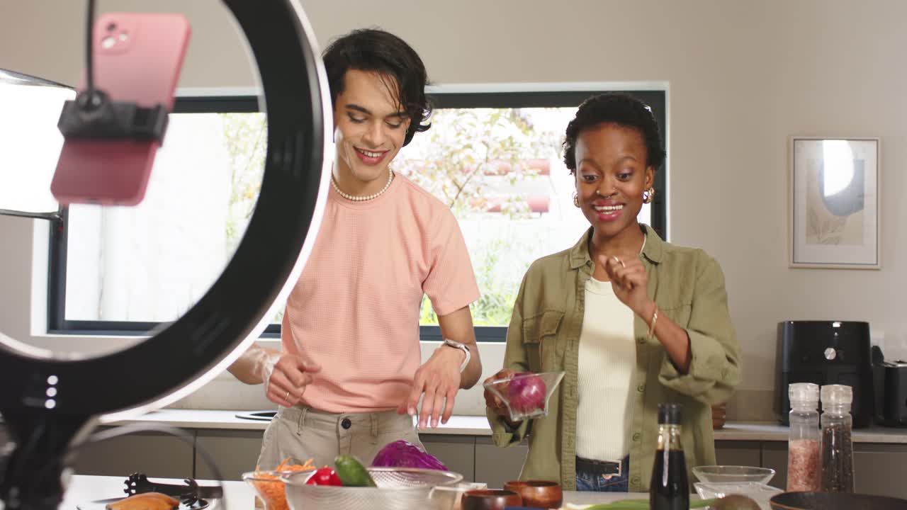 Diverse co-hosts initiating cooking tutorial by adjusting camera setup and slicing onion in kitchen