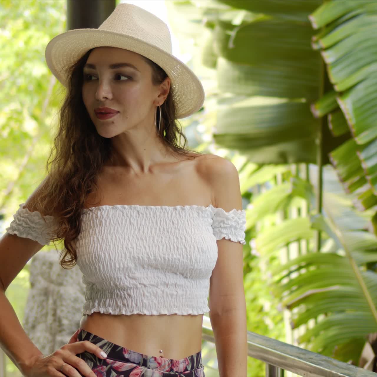 발코니에서 모자를 조정하는 자신감 있는 여성