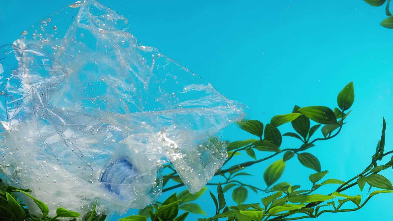 Bottiglia e sacchetto di plastica inquinano un limpido ambiente sottomarino blu.