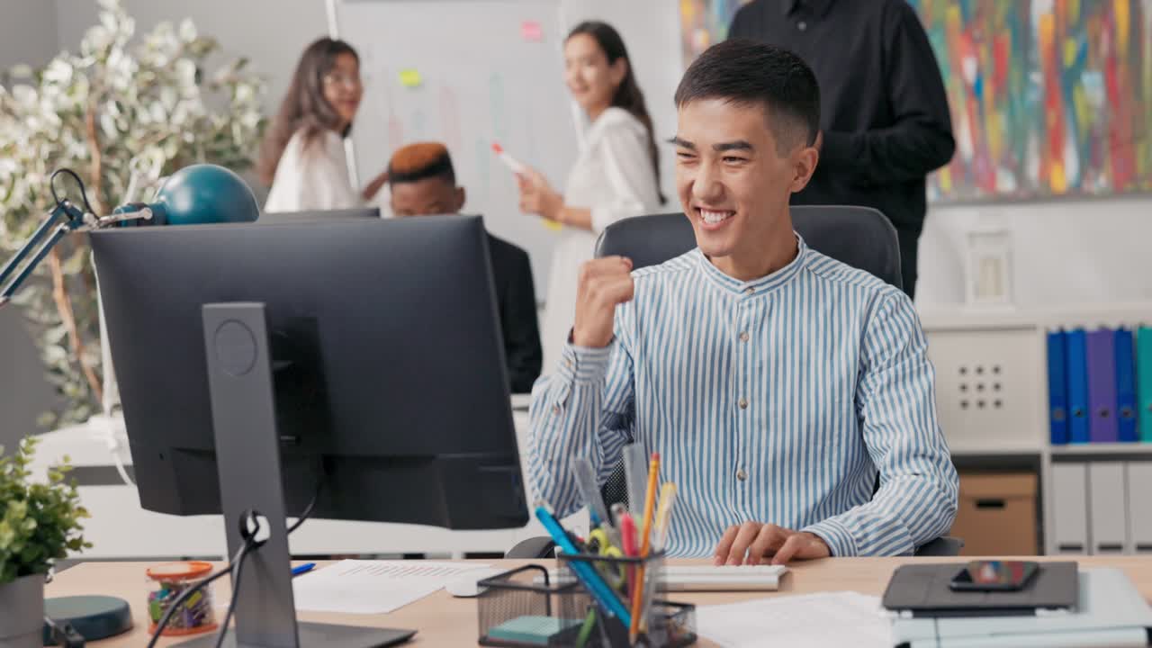 A man of Asian-Korean beauty is sitting an office computer, using a web ...