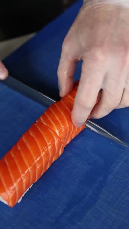 el chef está preparando un rollo de sushi de salmón.