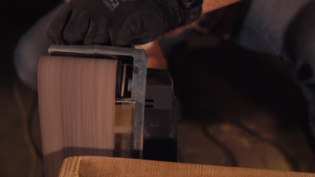 vista de primer plano de una persona que lijando una pieza de madera con una lijadora eléctrica