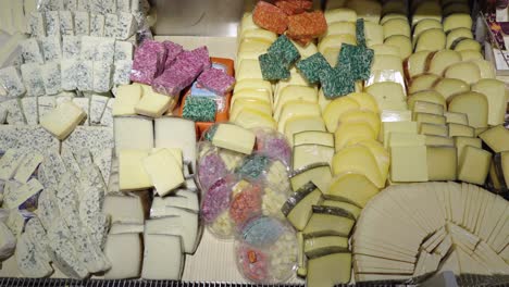 many different cheeses are on display in the store. retail of gastronomic goods in the supermarket. smooth pan of camera