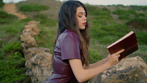 Woman-reader-enjoying-book-sitting-on-grass-rocky-hill-close-up.-Girl-reading.