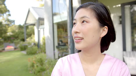 smiling nurse in pink uniform enjoying outdoor time at home, feeling happy