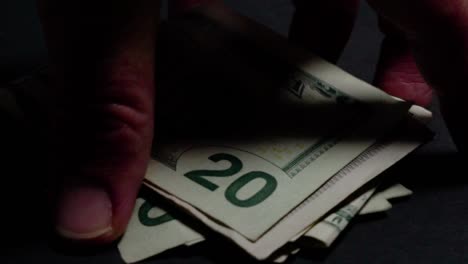 Cash-grab,-Hand-picks-up-pile-of-twenty-dollar-bills-on-black-background-CLOSEUP