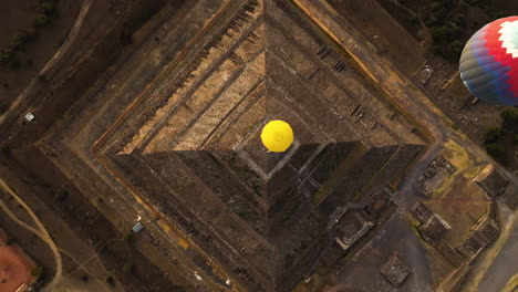 top down drone shot of hot air balloons above a pyramid in sunny teotihuacan, mexico