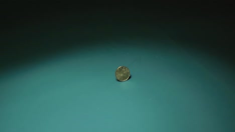 slowly moving footage of a 20 cent euro coin spinning and wobbling slightly before coming to a complete stop, landing on one side in 4k