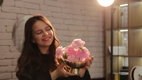 a woman holds a bouquet of pink flowers in a stylish interior enhancing the atmosphere