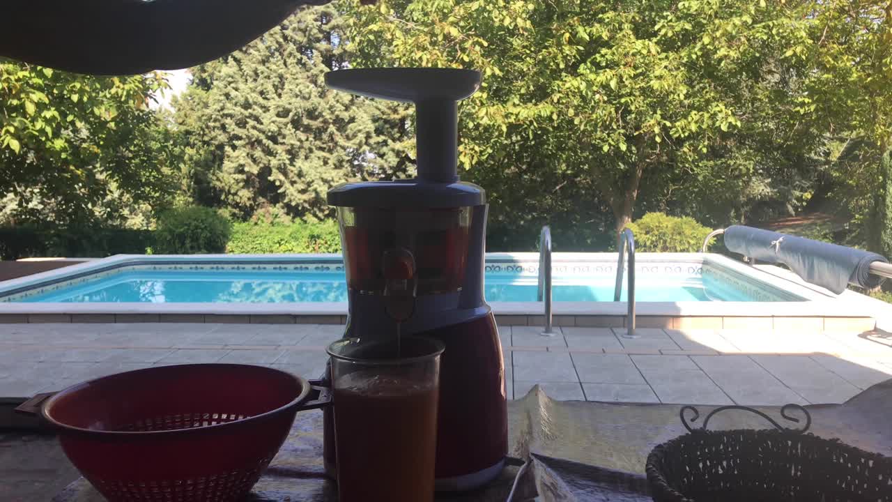Healthy living and juicing wild apples with outdoor rural swimming pool background in slow motion