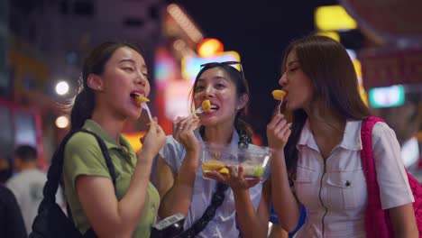 tres amigos disfrutando de comida callejera en un mercado nocturno