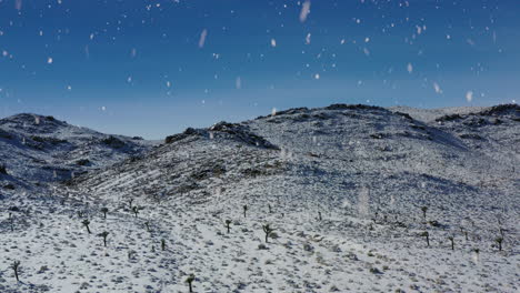 paisaje desértico montañoso de invierno durante las nevadas, vista aérea de vuelo hacia atrás