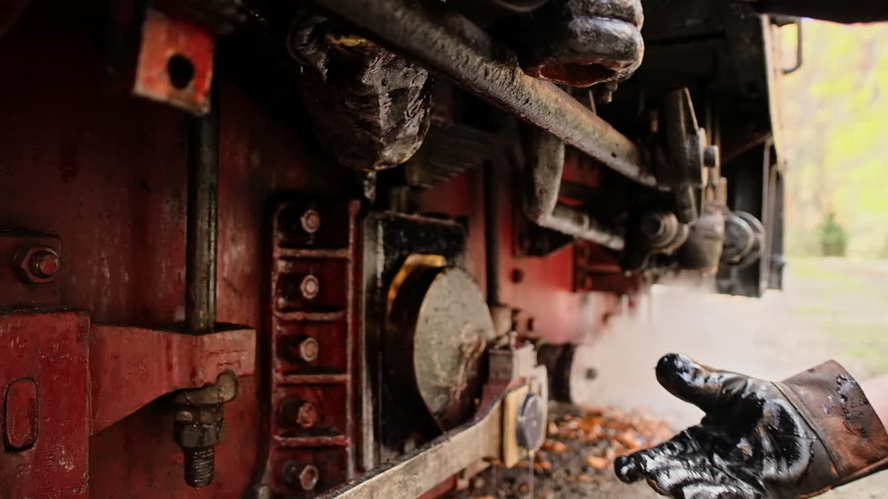 Mechanic adding oil in mechanisms of stopped steam train Mocanita at a railway station, Romania. Slow motion