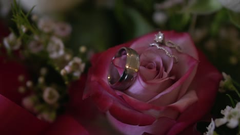 Close-up-of-bride-and-groom-wedding-rings-placed-on-a-bouquet-of-beautiful-flowers,-slow-motion-shot