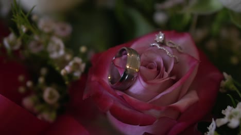 close up of bride and groom wedding rings placed on a bouquet of beautiful flowers, slow motion shot