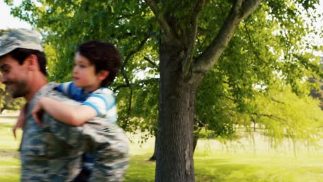 Lächelnder-Armeesoldat-Gibt-Seinem-Sohn-Huckepackfahrt-Im-Park