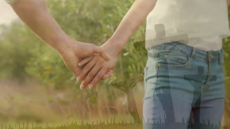 animation of couple holding hands standing in green field in countryside over silhouettes of three c