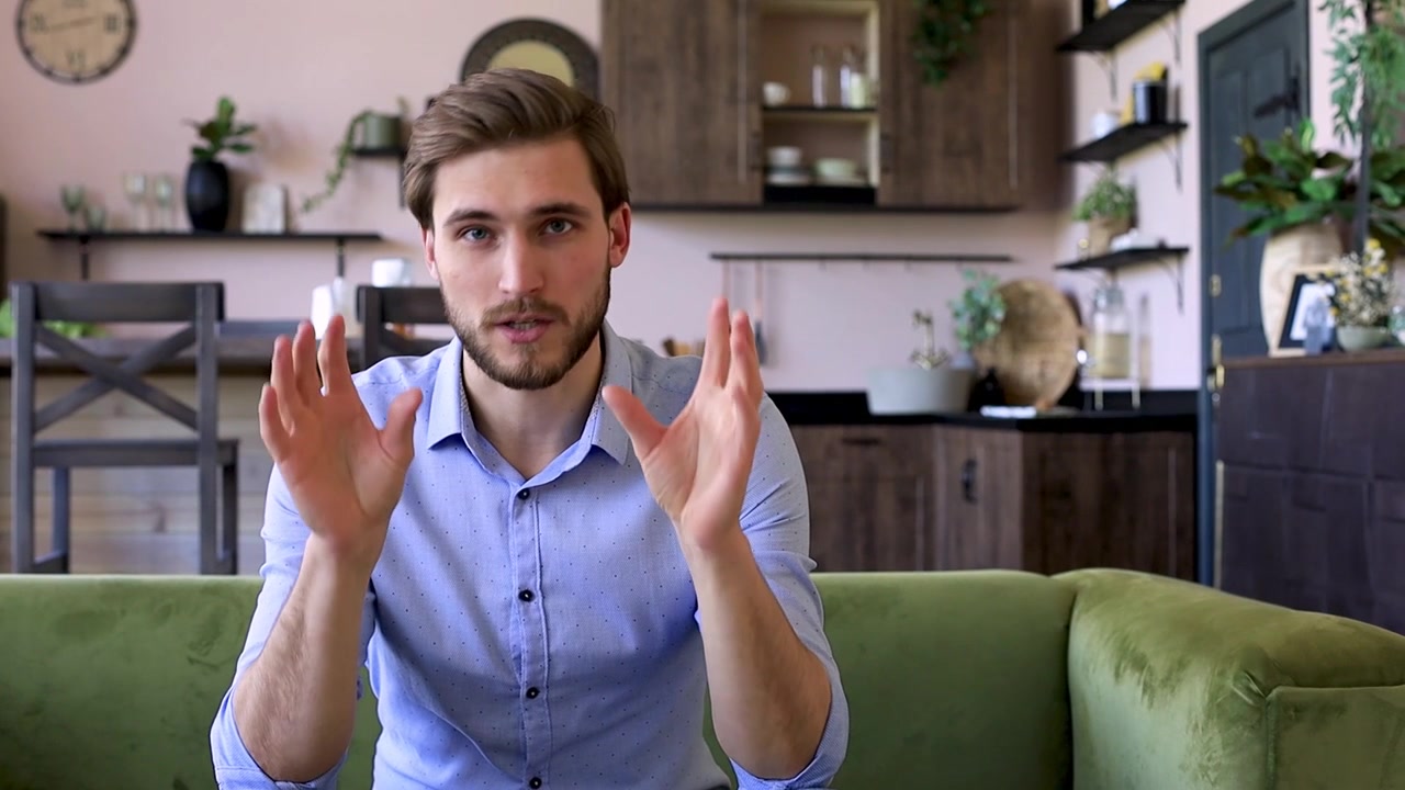 Young Man Talking and Gesturing During a Video Call at Home