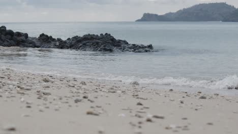 olas del océano rompiendo en la playa y rocas negras en una isla
